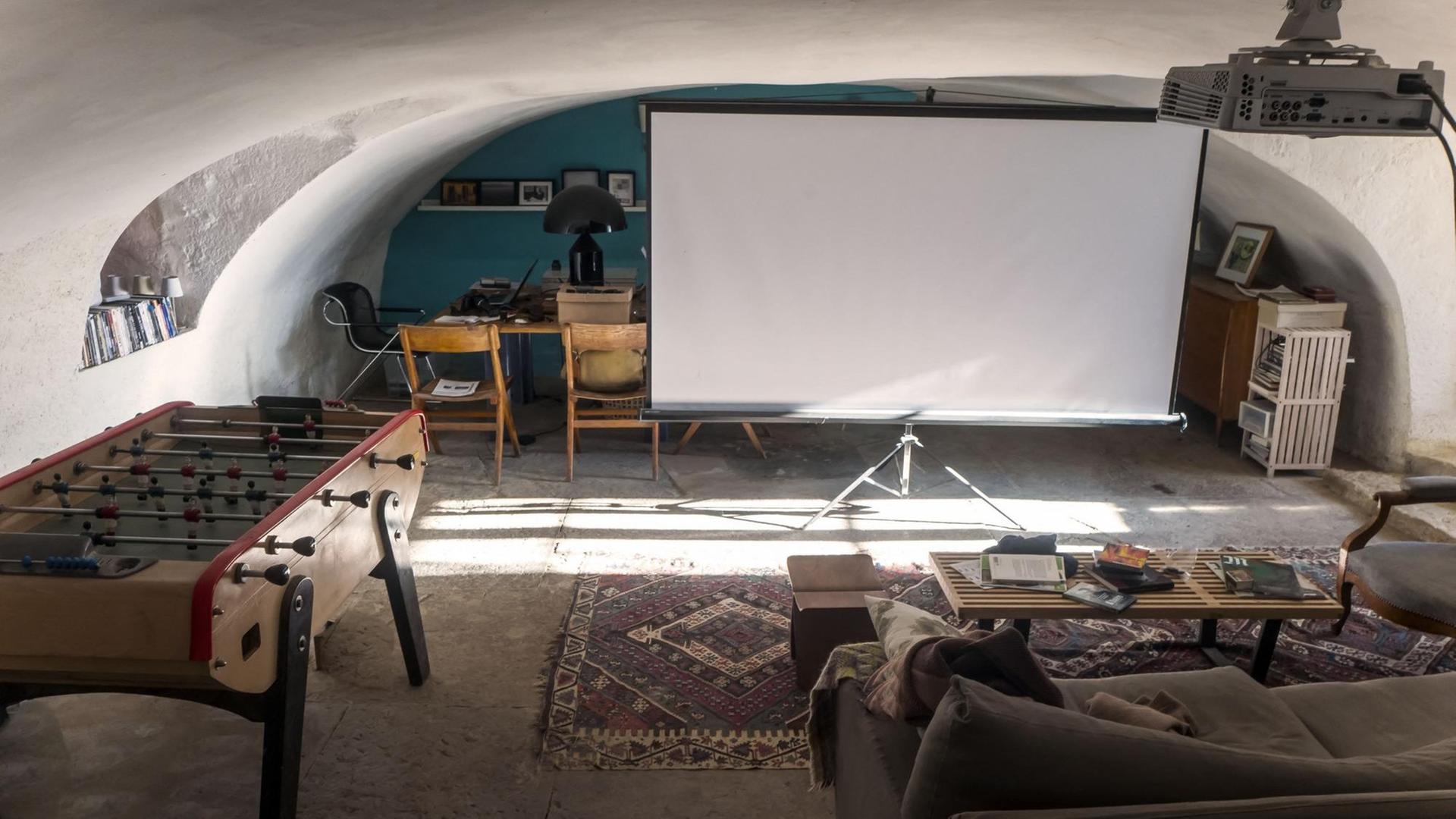 Ein Sofa, davor eine Leinwand und ein Videoprojektor.
