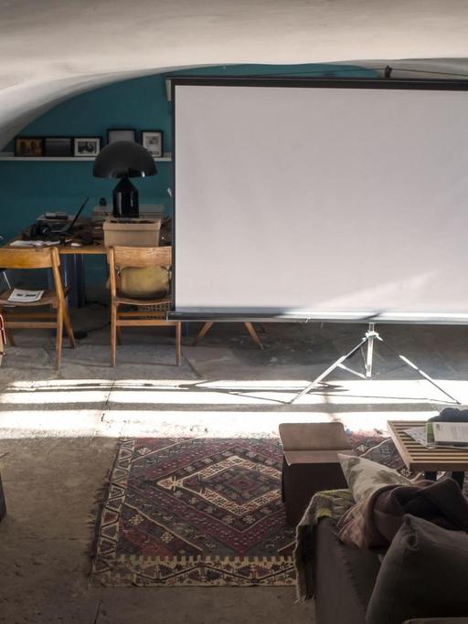 Ein Sofa, davor eine Leinwand und ein Videoprojektor.
