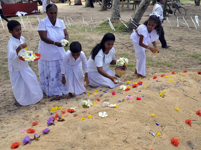 Trauernde legen Blumen an Gräbern von Tsunami-Opfern ab, die der Flutwelle vom Dezember 2004 zum Opfer fielen.