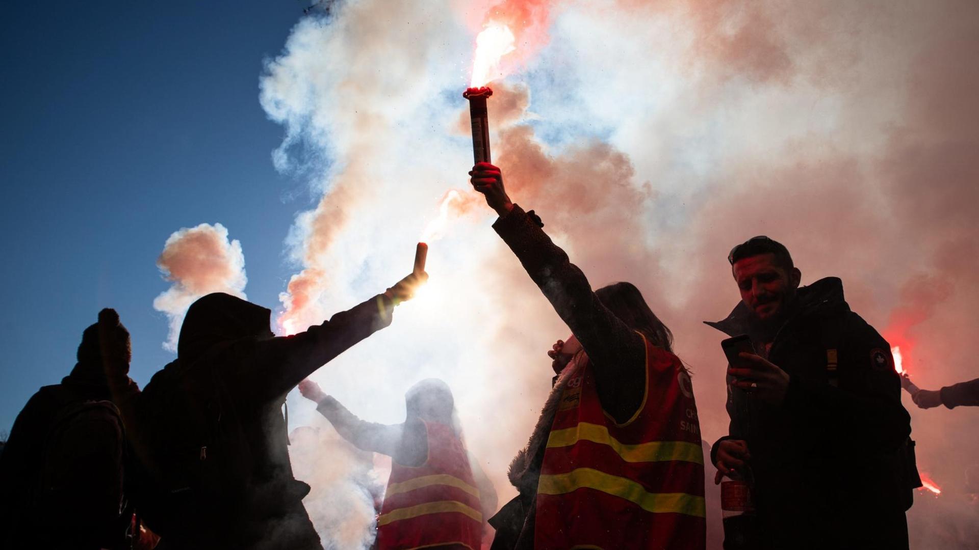 Protestierende halten brennende und rauchende Fackeln hoch. Protestierende halten brennende und rauchende Fackeln hoch.