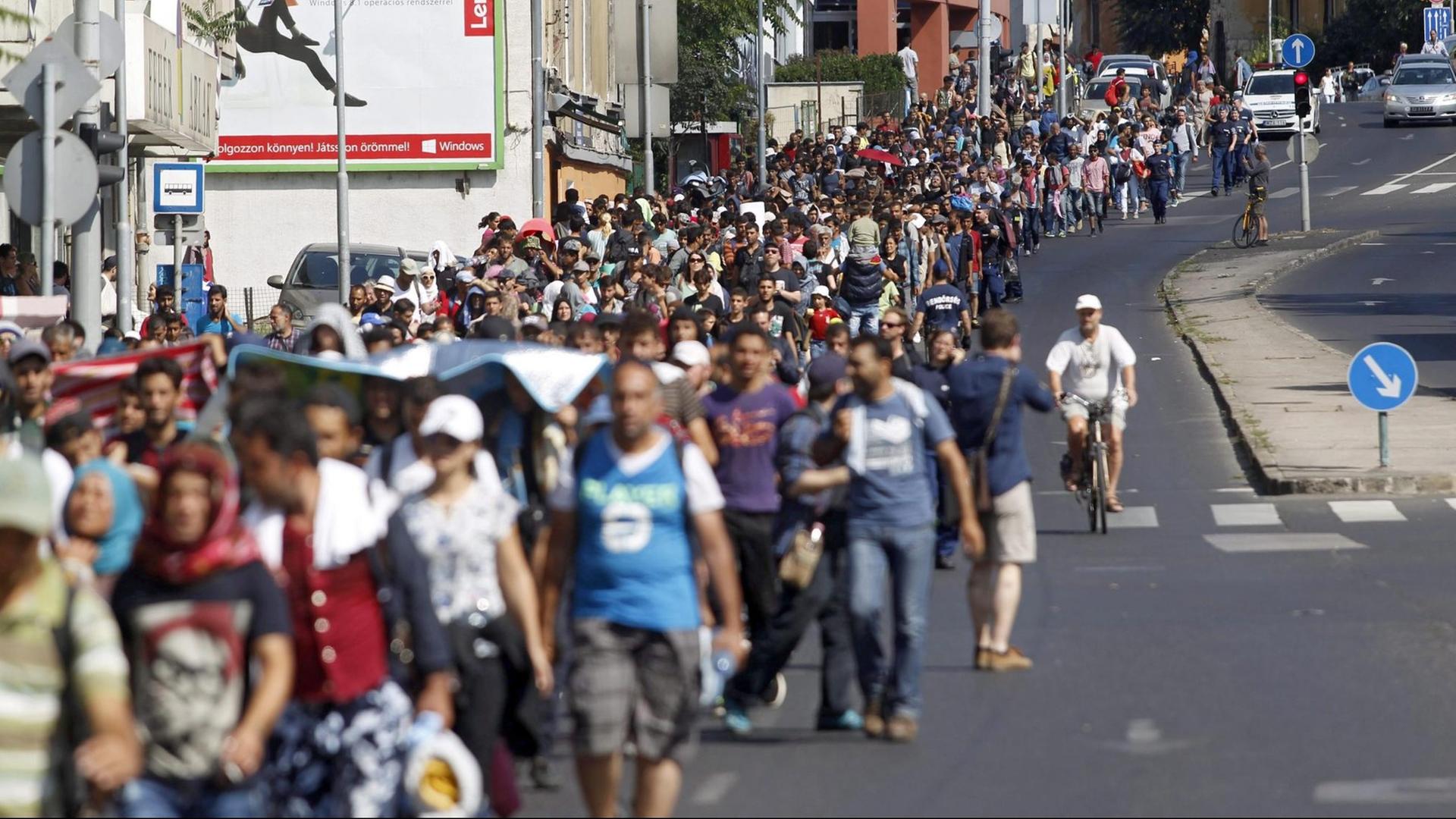 Flüchtlinge laufen eine Straße in Budapest entlang. Flüchtlinge laufen eine Straße in Budapest entlang.