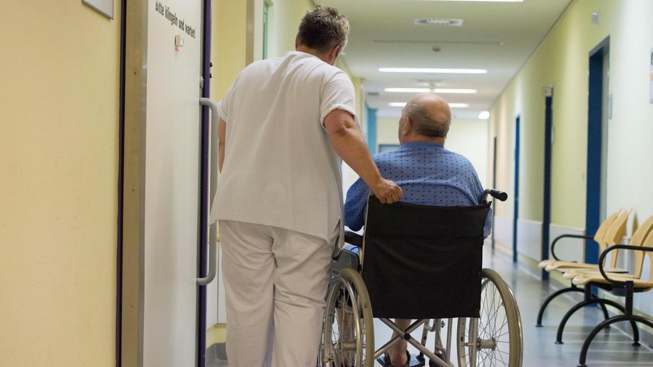 Eine Krankenschwester im Flur des Klinikums Carl Gustav Carus in Dresden neben einem Patienten im Rollstuhl. Eine Krankenschwester im Flur des Klinikums Carl Gustav Carus in Dresden neben einem Patienten im Rollstuhl.