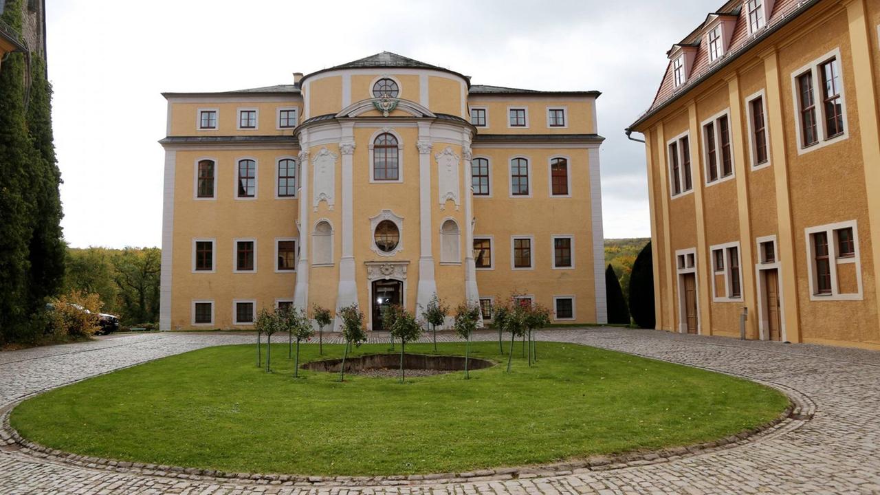 Blick auf eine runde Auffahrt direkt vor einem gelben, kleinen Schlossbau. Blick auf eine runde Auffahrt direkt vor einem gelben, kleinen Schlossbau.