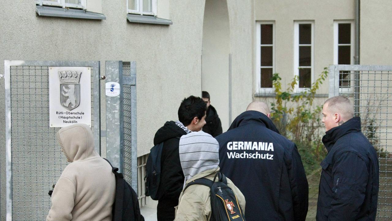 Mitarbeiter des privaten Wachchutzes Germania stehen zusammen mit einigen Schülern 2007 vor dem Eingang der Rütli-Hauptschule in Berlin-Neukölln. Mitarbeiter des privaten Wachchutzes Germania stehen zusammen mit einigen Schülern 2007 vor dem Eingang der Rütli-Hauptschule in Berlin-Neukölln.