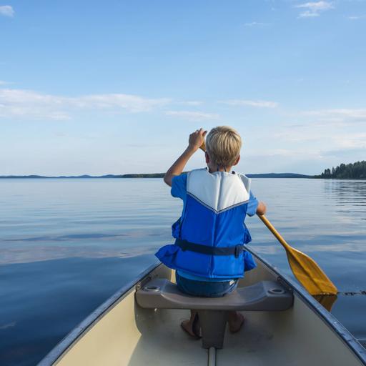 Aufnahme eines paddelnden Kindes von hinten mit Blick auf den weiten See.