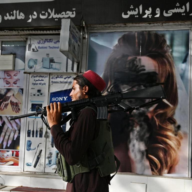 Ein Taliban-Kämpfer geht am 18. August 2021 in Shar-e-Naw in Kabul an einem Schönheitssalon vorbei, in dem Bilder von Frauen mit Sprühfarbe verunstaltet wurden.