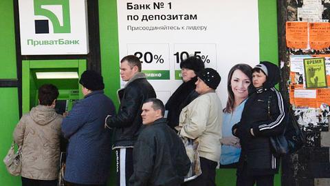 Ukrainische Bankkunden stehen Schlange an einem Geldautomaten.