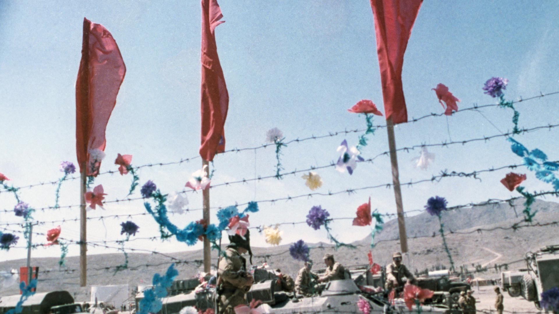 Sowjetische Armeefahrzeuge und Panzer am 15. Mai 1988 hinter einem mit künstlichen Blumen und roten Fahnen dekorierten Stacheldrahtzaun: An diesem Tag begann der sowjetischeTruppenabzug. Sowjetische Armeefahrzeuge und Panzer am 15. Mai 1988 hinter einem mit künstlichen Blumen und roten Fahnen dekorierten Stacheldrahtzaun: An diesem Tag begann der sowjetischeTruppenabzug.