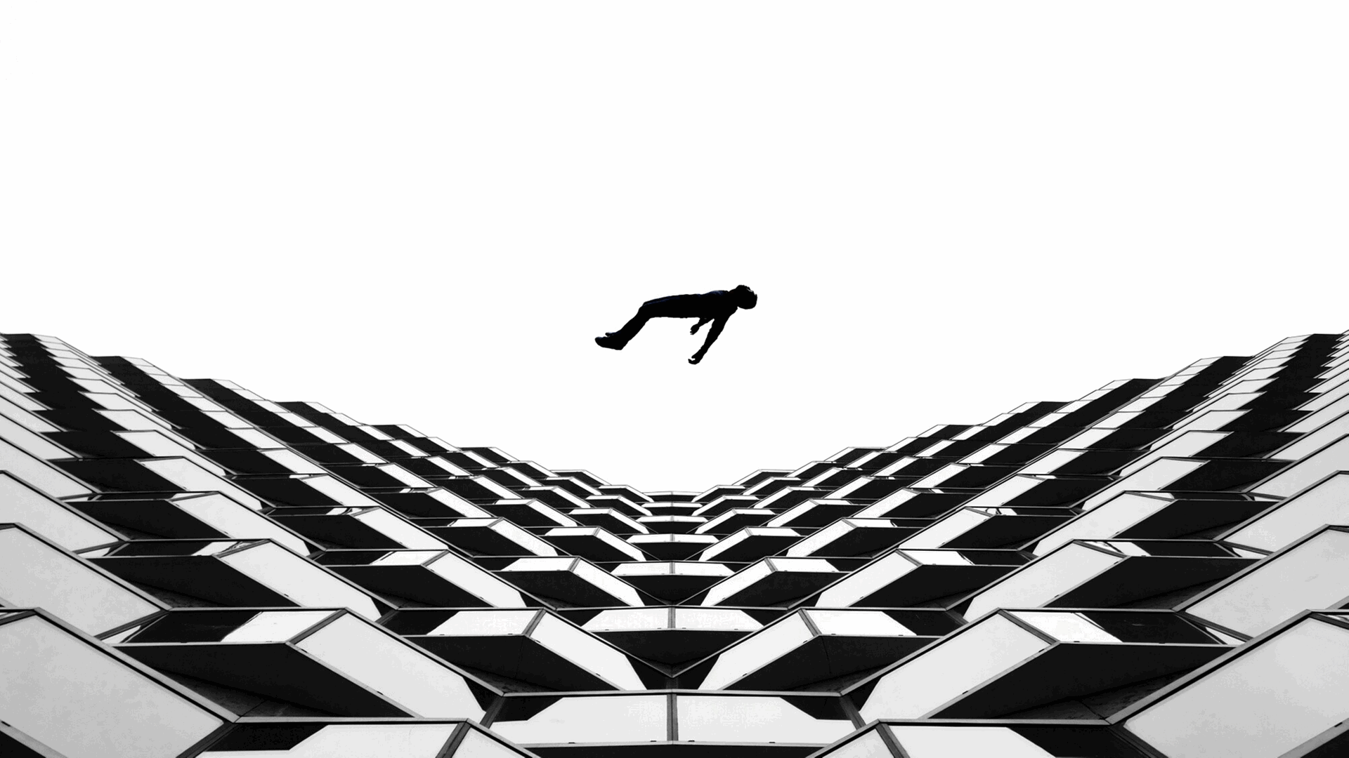 Titel: Körper der Gewalt - Eine Person fällt von einem Hochhaus und fliegt in der Luft (schwarz-weiß-Aufnahme). Titel: Körper der Gewalt - Eine Person fällt von einem Hochhaus und fliegt in der Luft (schwarz-weiß-Aufnahme).