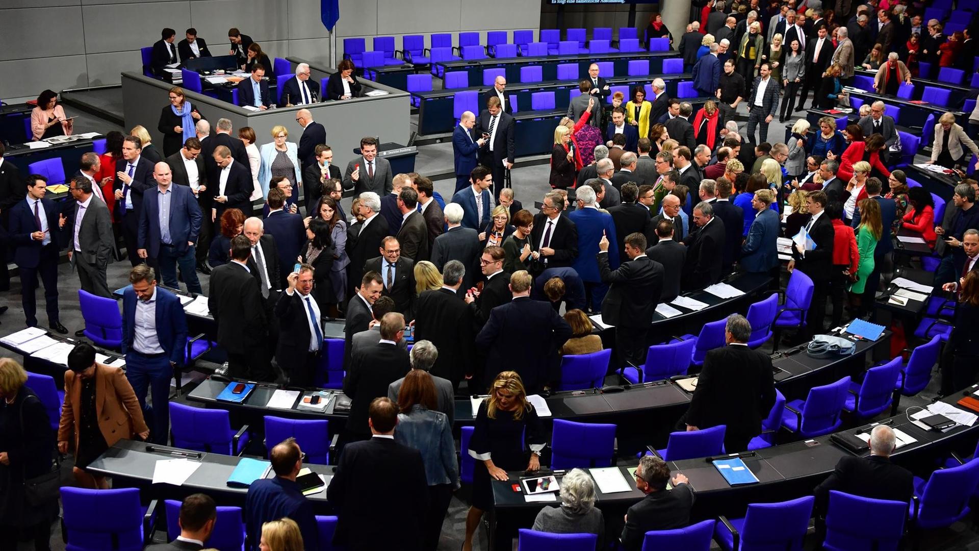 Abgeordnete stehen im Plenarsaal des Bundestages zwischen den Stühlen und unterhalten sich. Abgeordnete stehen im Plenarsaal des Bundestages zwischen den Stühlen und unterhalten sich.