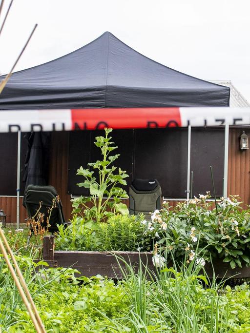 Blick auf eine Gartenlaube vor der ein Polizeiabsperrband gespannt ist