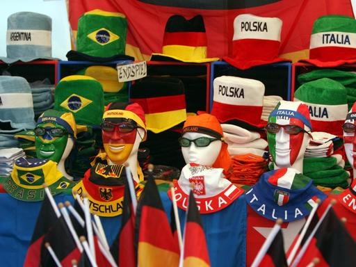 Fahnen, Kappen und Hüte in den Farben verschiedener Nationen dekorativ aufgestapelt