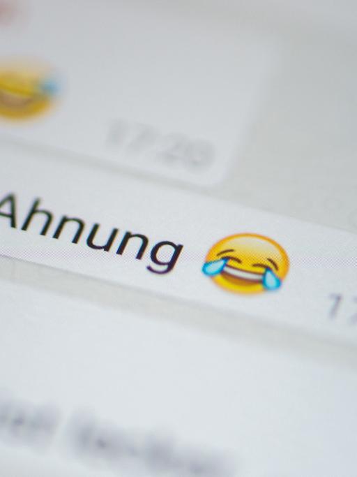 Ein Smartphone-Nutzer tippt auf ein Emoji, um es in eine WhatsApp-Nachricht einzufügen.