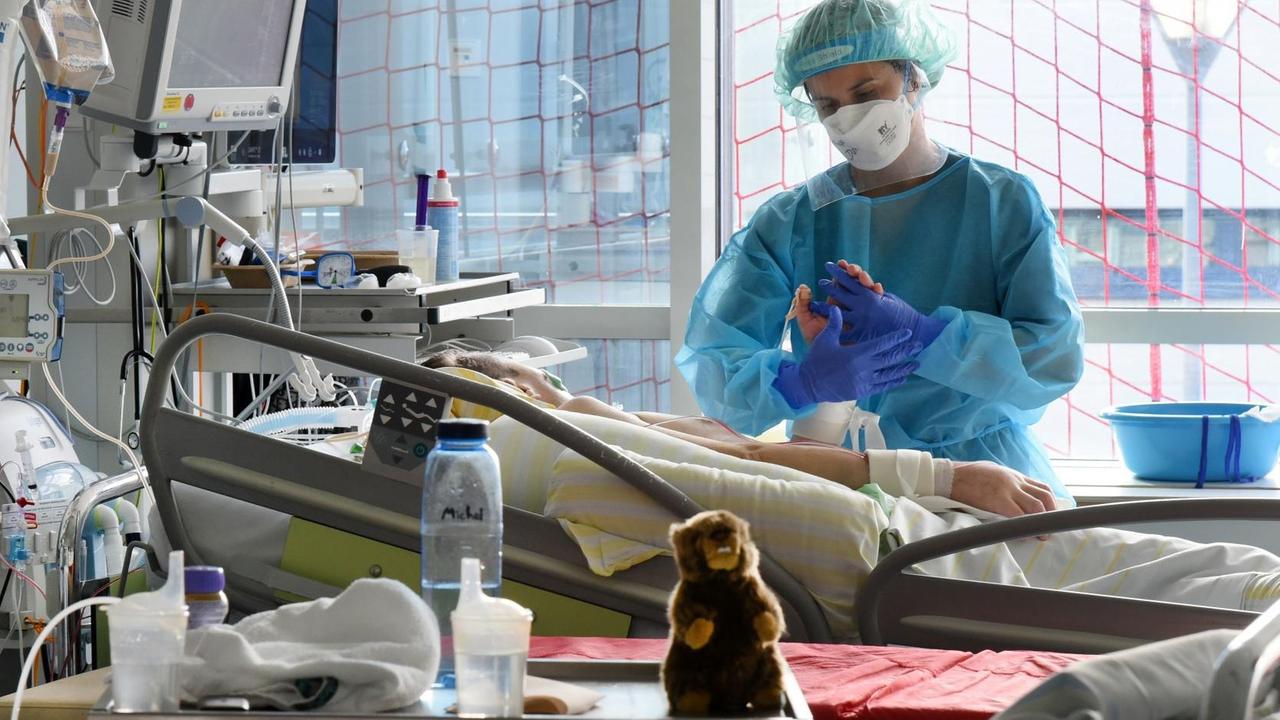 Auf der Covid-Station, einem Bereich der Operativen Intensivstation des Universitätsklinikums Leipzig, steht eine Physiotherapeutin am Bett einer Patientin.
