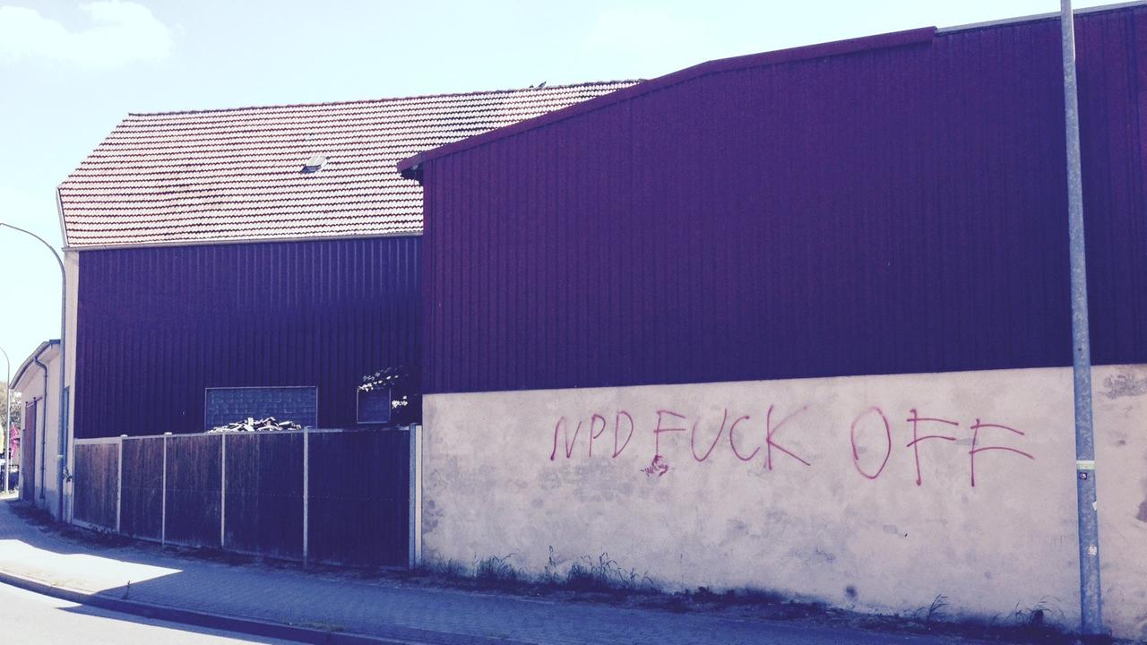 An einer Hauswand in einem Dorf hat jemand "NPD Fuck off" gesprüht.