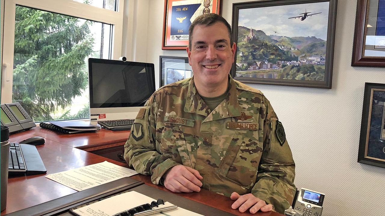 General Mark August sitzt an seinem Schreibtisch und lächelt in die Kamera.