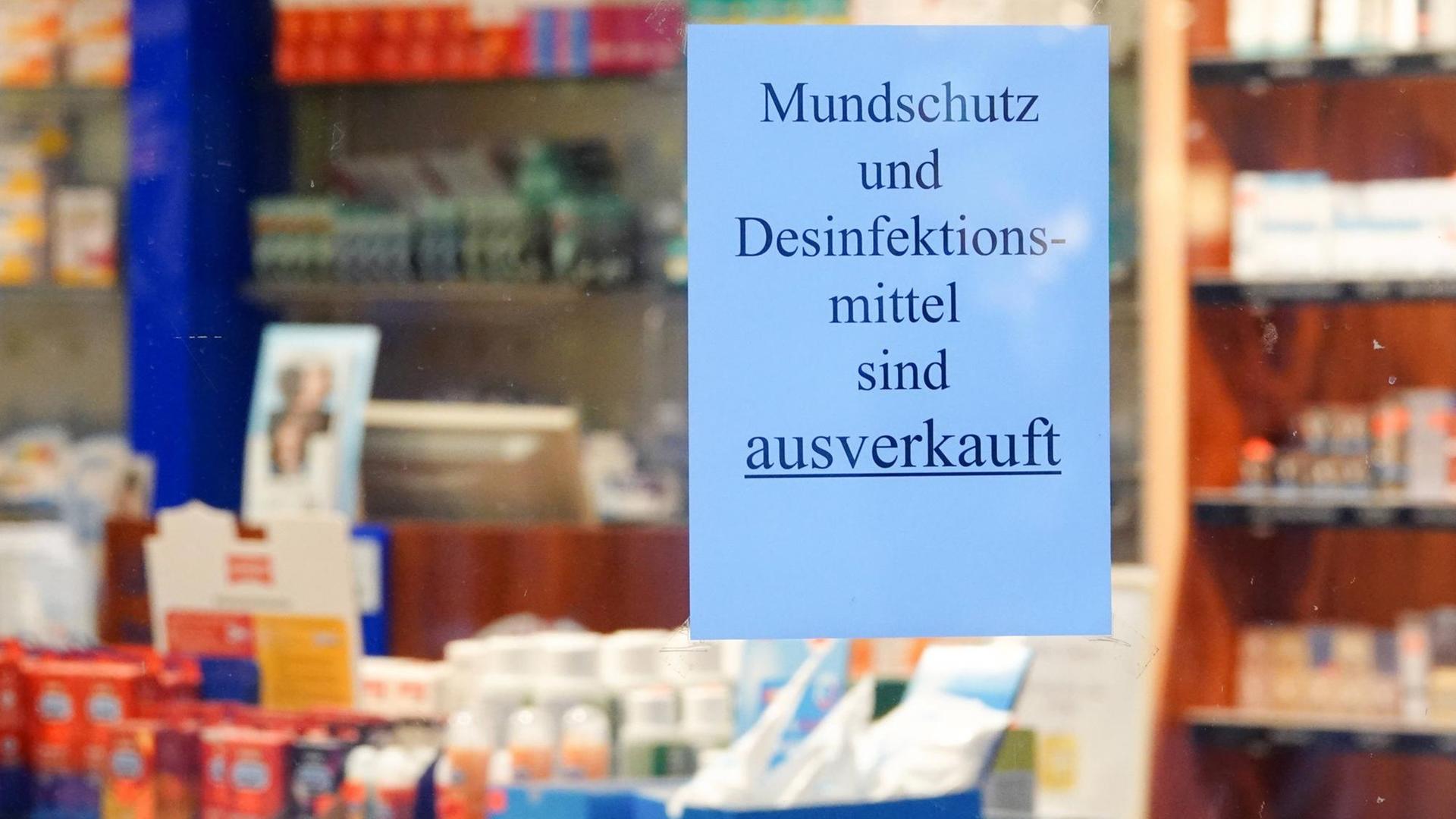 Ein Schild mit der Aufschrift Mundschutz und Desinfektionsmittel sind ausverkauft hängt im Fenster einer Apotheke.