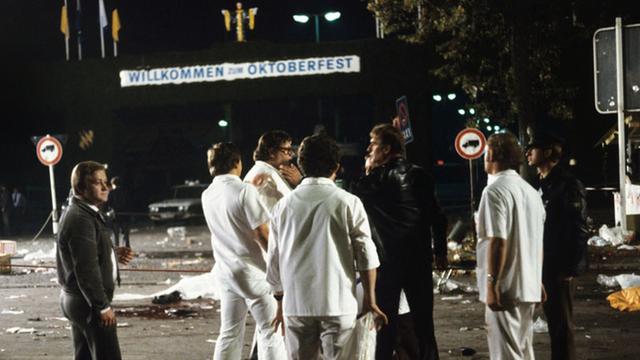 Mitarbeiter der Spurensicherung stehen nach dem Bombenanschlag auf dem Münchener Oktoberfest am 26.09.1980 in der Dunkelheit vor einem Bild der Verwüstung.