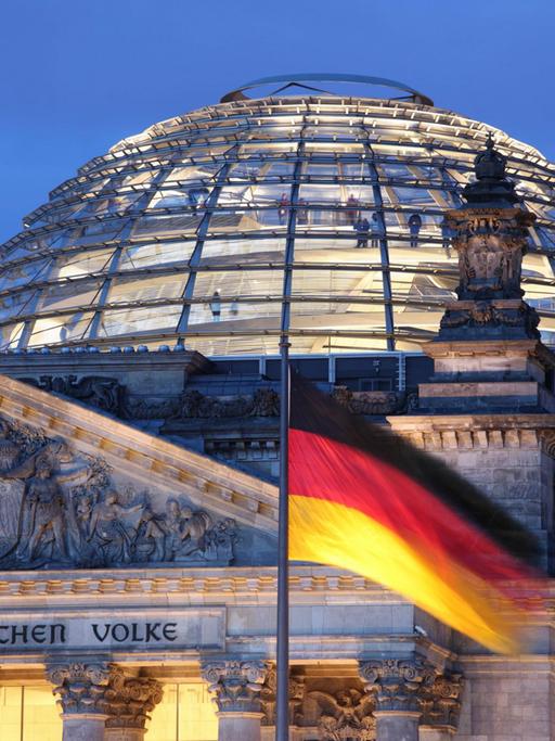 Vor der Reichstagskuppel und dem Reichstag weht eine schwarz-rot-goldene Deutschland-Fahne