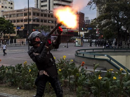 Ein Mitglied der venezolanischen Nationalpolizei schießt einen Tränengaskanister mit einem Gewehr ab, um regierungskritische Demonstranten zu vertreiben, aufgenommen 2014.