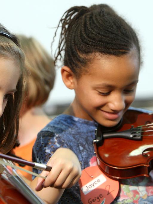 Naomi (l) und Joyce probieren am Dienstag (26.08.2008) ihre neuen Geigen aus, die der Bundespräsident zuvor an Grundschüler der Martin-Luther-Grundschule im Rahmen der Initiative «Jedem Kind ein Instrument» in Gelsenkirchen übergab.