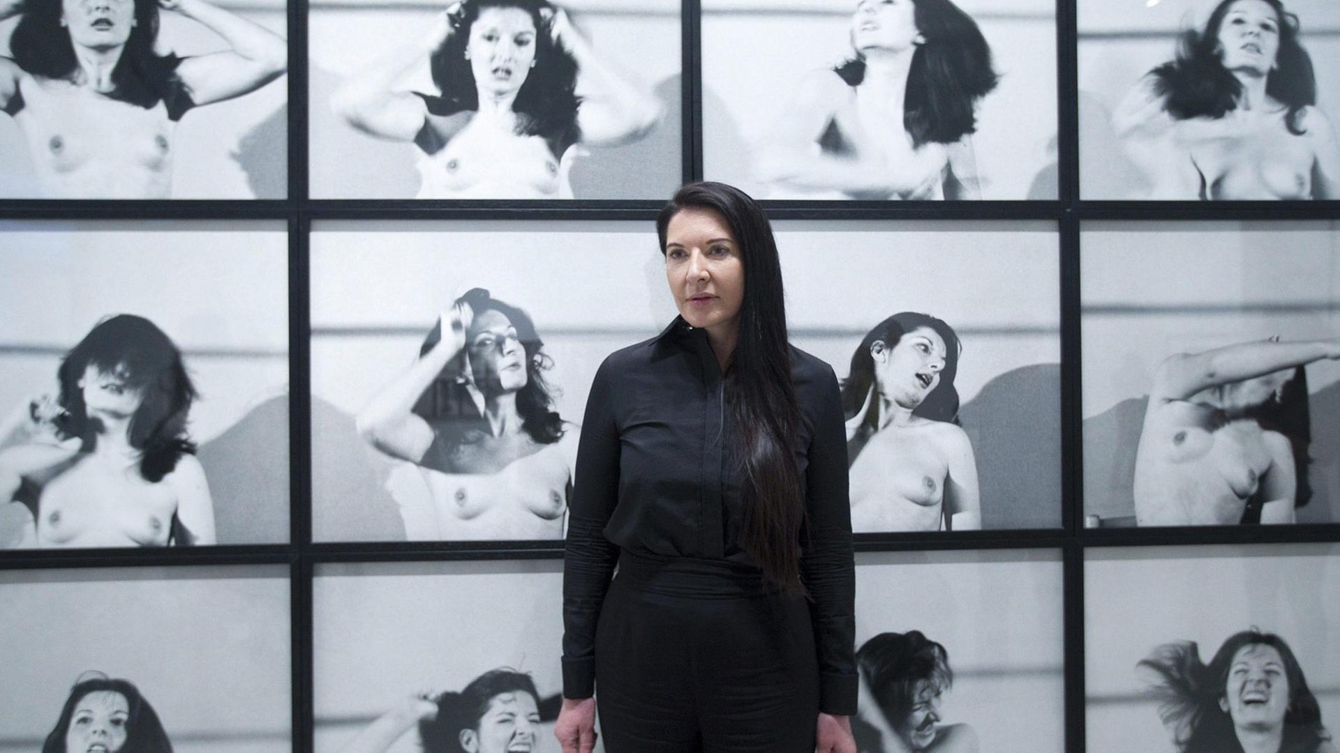 Die serbische Performancekünstlerin Marina Abramovic steht vor einer Fotowand mit Bildern von einer ihrer Performances.