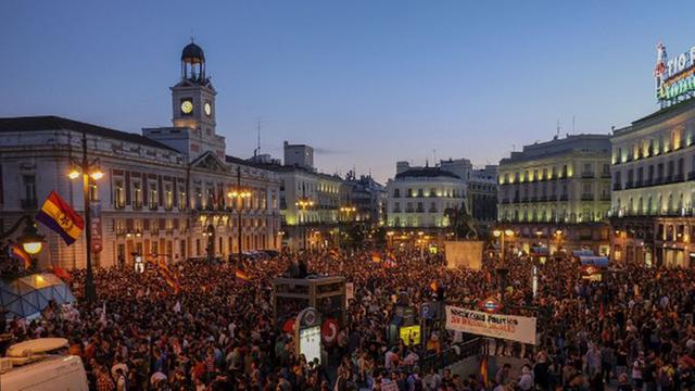 Auf einem zentralen Platz in der spanischen Hauptstadt Madrid schwenken Demonstranten Fahnen und halten Plakate gegen die Monarchie in die Höhe.