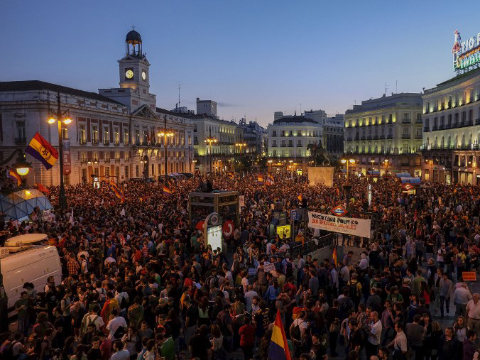 Auf einem zentralen Platz in der spanischen Hauptstadt Madrid schwenken Demonstranten Fahnen und halten Plakate gegen die Monarchie in die Höhe.