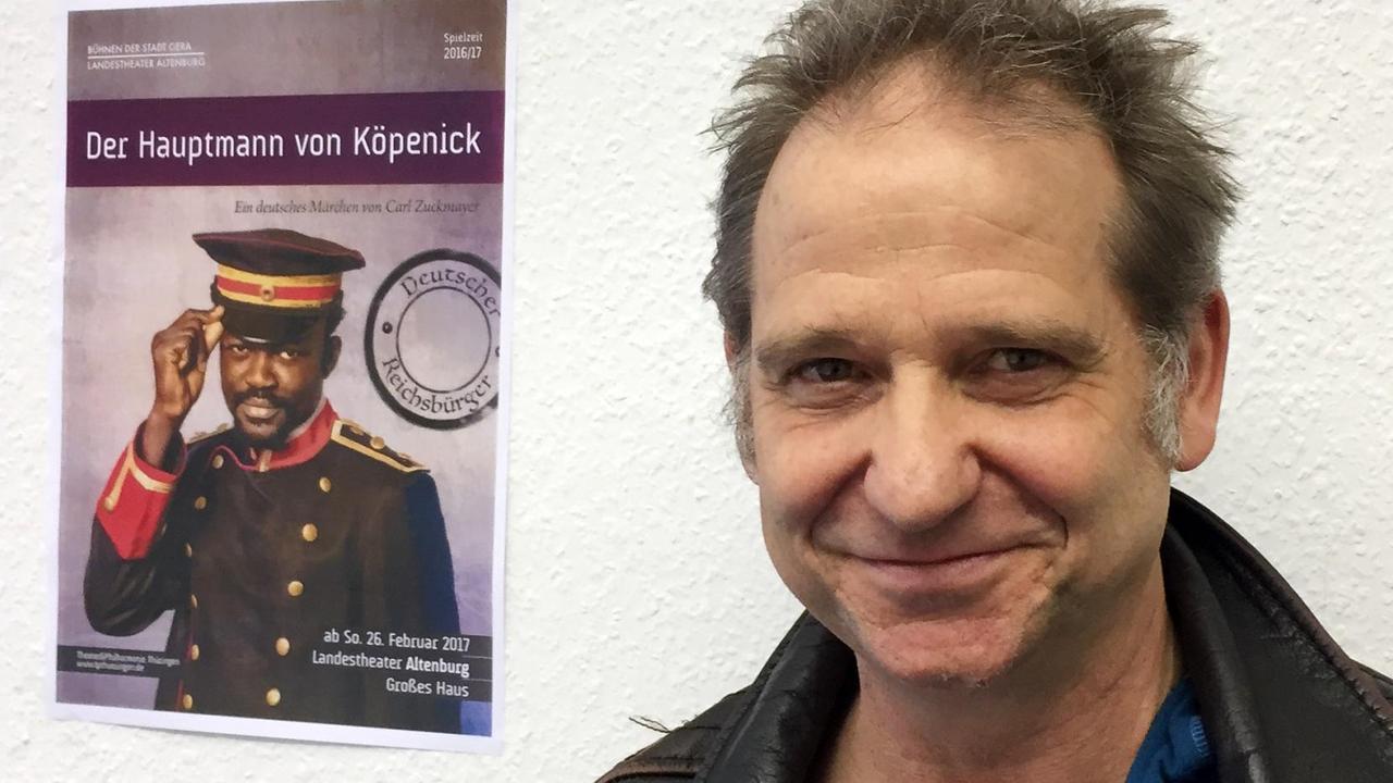 Bernhard Stengele lacht in die Kamera. Im Hintergrund an der Wand hängt ein Plakat von "Der Hauptmann von Köpenick". Bernhard Stengele lacht in die Kamera. Im Hintergrund an der Wand hängt ein Plakat von "Der Hauptmann von Köpenick".