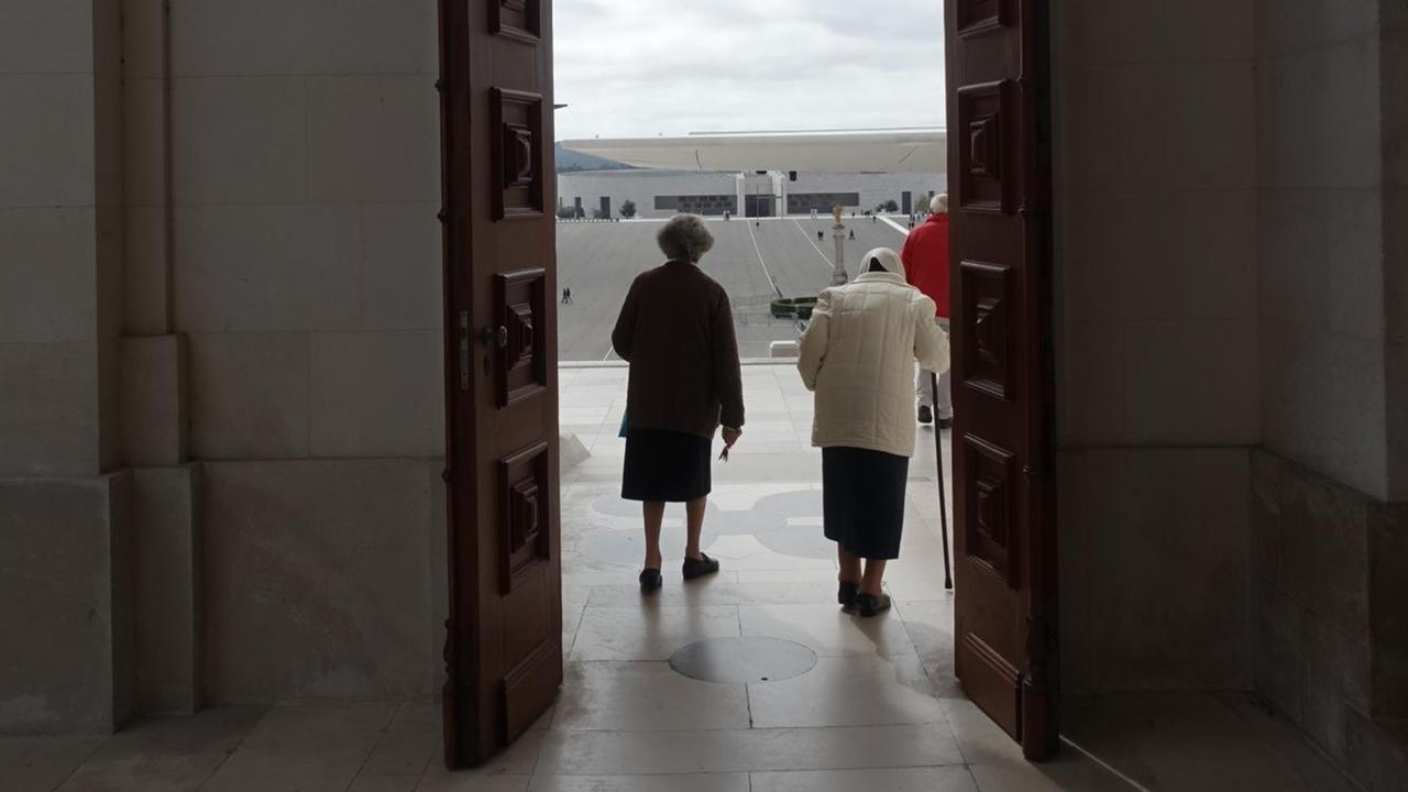 Das Bild zeigt zwei alte Damen, die durch die Tür der Kathedrale von Fátima verlassen. Das Bild zeigt zwei alte Damen, die durch die Tür der Kathedrale von Fátima verlassen.