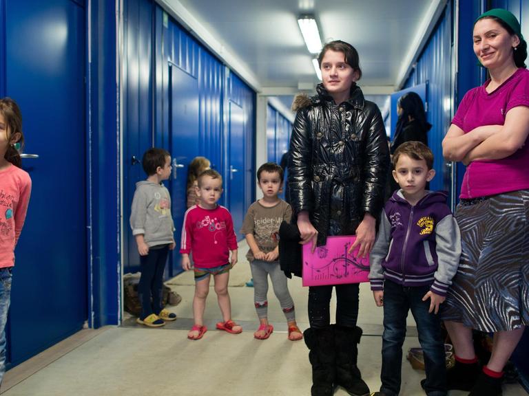 Eine Frau und viele Kinder aus Tschetschenien stehen am 26.02.2013 in einem Wohncontainer auf dem Gelände der Zentralen Ausländerbehörde des Landes Brandenburg in Eisenhüttenstadt (Brandenburg).