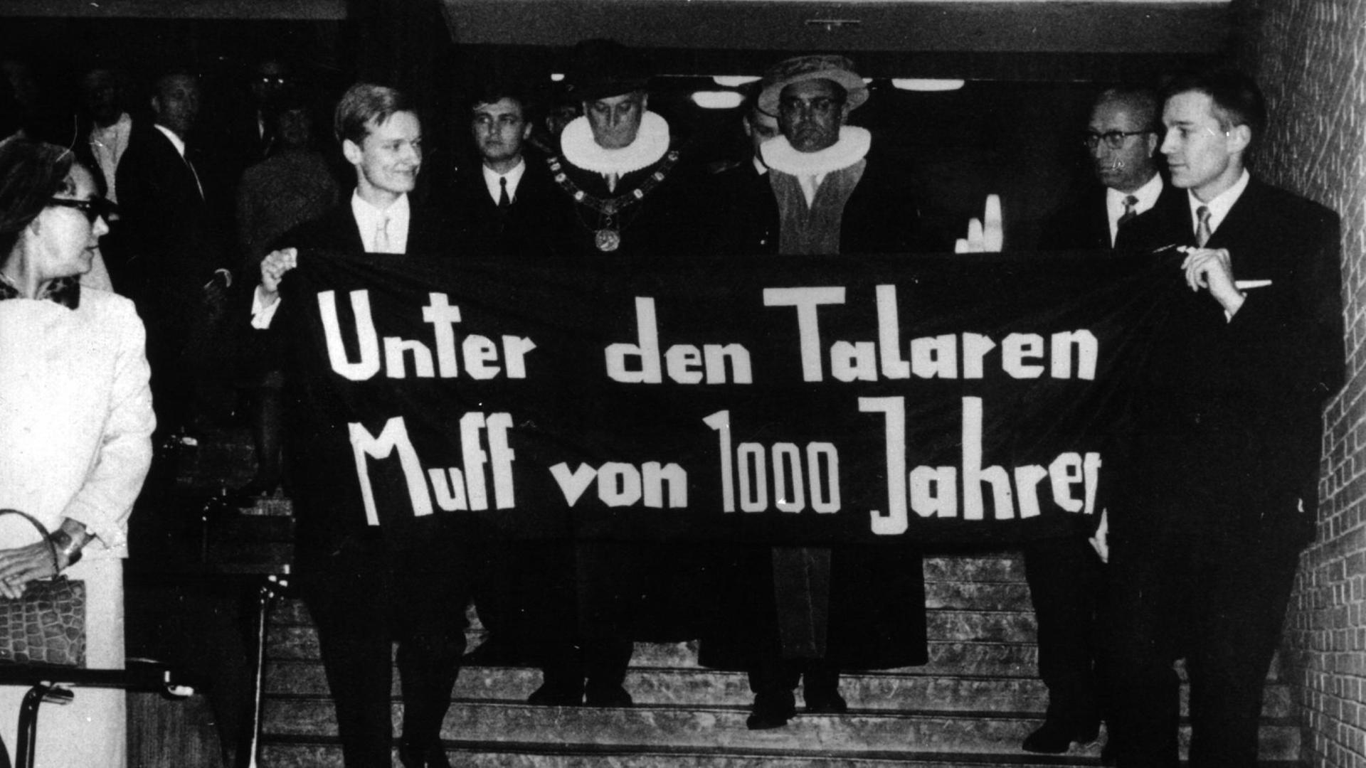 "Unter den Talaren Muff von 1000 Jahren" steht auf einem Spruchband, das Studenten am 09.11.1967 beim Eintritt des neuen und des alten Rektors der Universität Hamburg ins Auditorium Maximum halten. Links hinter dem Spruchband der ehemalige Rektor, Prof. Dr. med. Schöfer, rechts der neue Rektor, Prof. Dr. rer. pol. Ehrlicher. "Unter den Talaren Muff von 1000 Jahren" steht auf einem Spruchband, das Studenten am 09.11.1967 beim Eintritt des neuen und des alten Rektors der Universität Hamburg ins Auditorium Maximum halten. Links hinter dem Spruchband der ehemalige Rektor, Prof. Dr. med. Schöfer, rechts der neue Rektor, Prof. Dr. rer. pol. Ehrlicher.