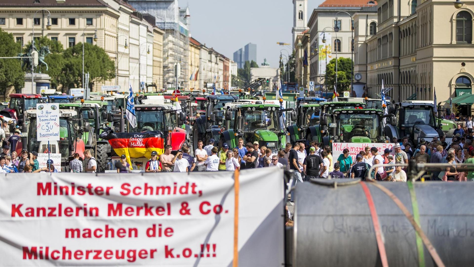Zahlreiche Traktoren stehen am 01.09.2015 in der Ludwigstraße in München (Bayern), während im Vordergrund ein Transparent mit der Aufschrift "Minister Schmidt, Kanzlerin Merkel & Co. machen die Milcherzeuger k.o.!!!". Hunderte Landwirte protestieren gegen sinkende Milchpreise. Foto: Marc Müller/dpa Zahlreiche Traktoren stehen am 01.09.2015 in der Ludwigstraße in München (Bayern), während im Vordergrund ein Transparent mit der Aufschrift "Minister Schmidt, Kanzlerin Merkel & Co. machen die Milcherzeuger k.o.!!!". Hunderte Landwirte protestieren gegen sinkende Milchpreise. Foto: Marc Müller/dpa