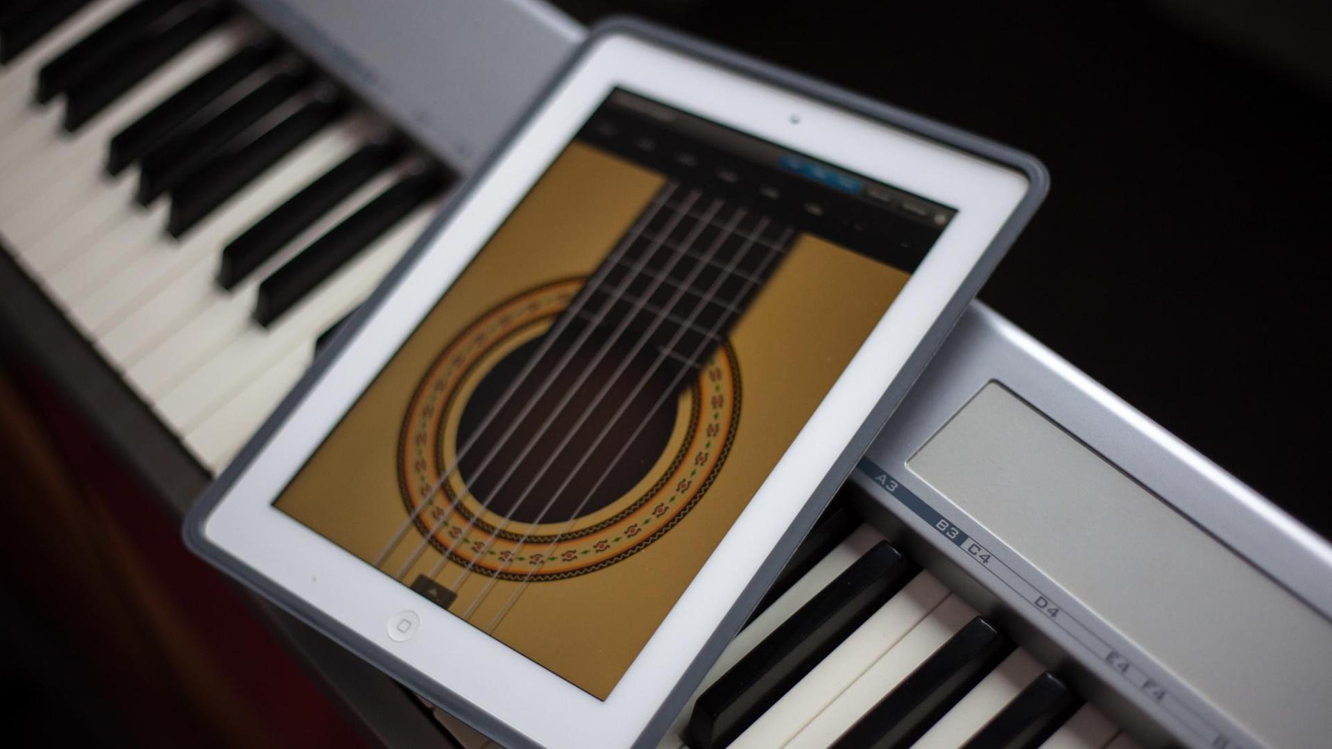 Auf einem Keyboard liegt ein Tablet Computer (iPad) mit einer Gitarren-App. Auf einem Keyboard liegt ein Tablet Computer (iPad) mit einer Gitarren-App.
