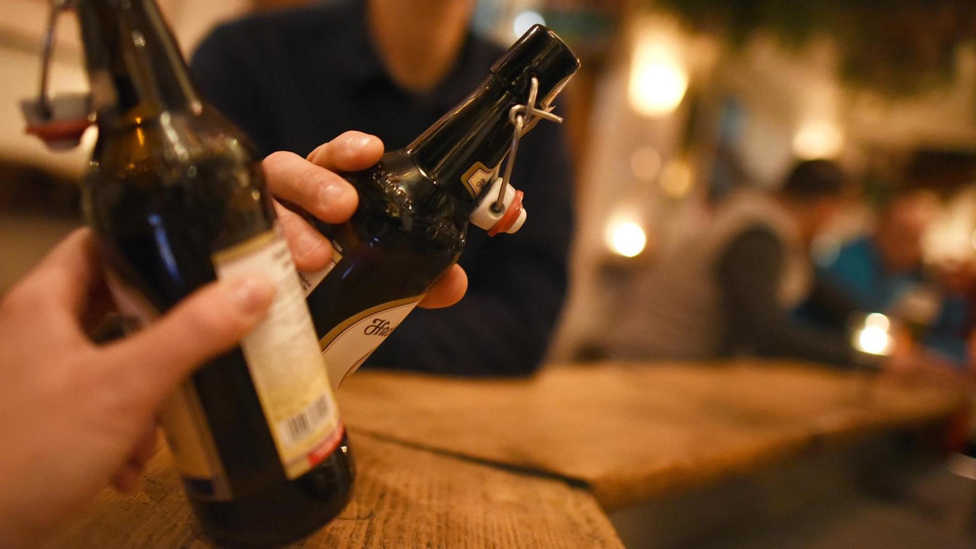 Zwei Personen stoßen am 30.11.2016 in Garmisch-Partenkirchen (Bayern) in einer Kneipe mit Bier in der Flasche an. Zwei Personen stoßen am 30.11.2016 in Garmisch-Partenkirchen (Bayern) in einer Kneipe mit Bier in der Flasche an.