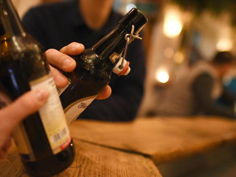 Zwei Personen stoßen am 30.11.2016 in Garmisch-Partenkirchen (Bayern) in einer Kneipe mit Bier in der Flasche an.
