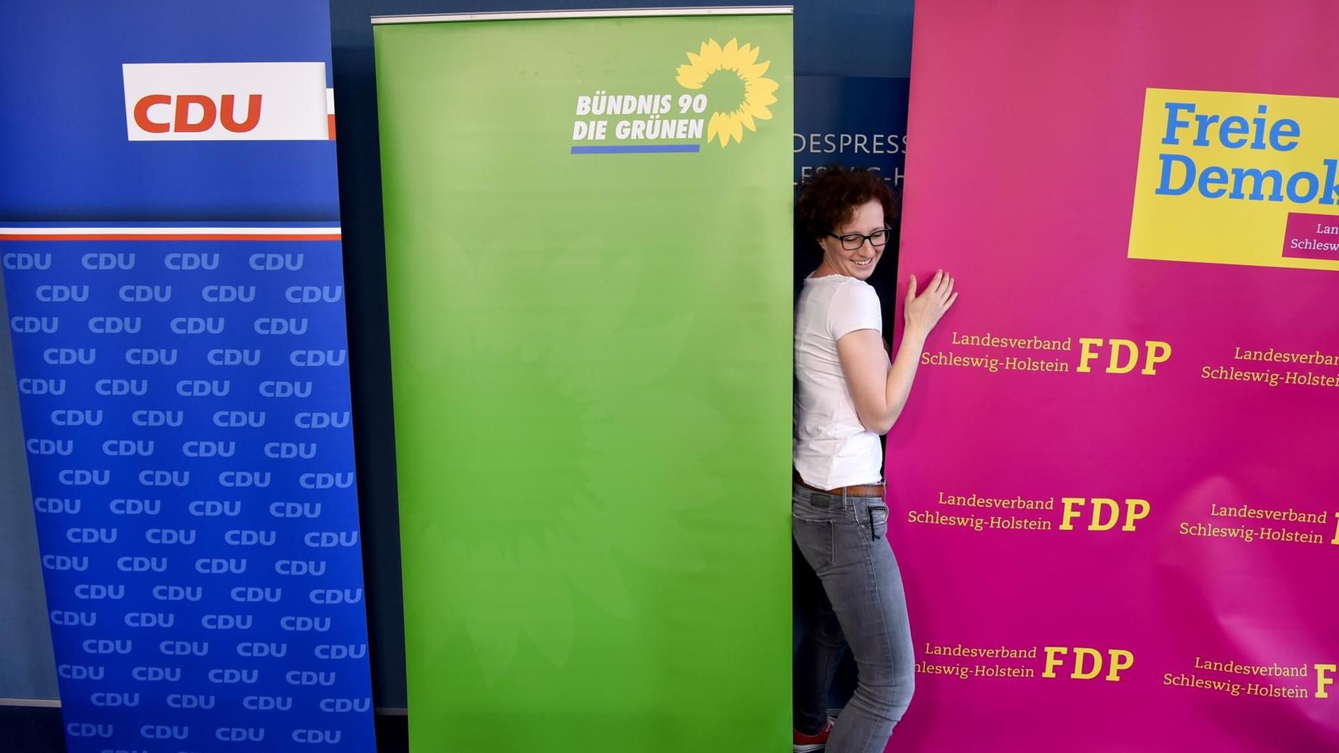 Ein Parteimitarbeiterin arrangiert am 14.06.2017 in Kiel (Schleswig-Holstein), vor einer Pressekonferenz im Landeshaus den Aufsteller der FDP. Zu sehen sind die Aufsteller der Parteien CDU, Bündnis 90/Die Grünen und FDP . Ein Parteimitarbeiterin arrangiert am 14.06.2017 in Kiel (Schleswig-Holstein), vor einer Pressekonferenz im Landeshaus den Aufsteller der FDP. Zu sehen sind die Aufsteller der Parteien CDU, Bündnis 90/Die Grünen und FDP .