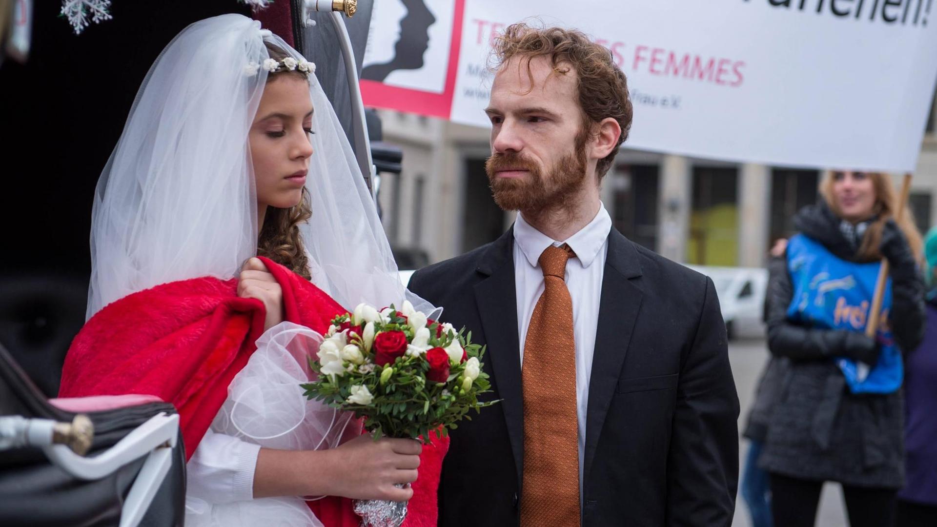 Zwei Darsteller von "Terre des Femmes" spielen ein junges Mädchen im Hochzeitskleid und einen älteren Mann im Anzug Zwei Darsteller von "Terre des Femmes" spielen ein junges Mädchen im Hochzeitskleid und einen älteren Mann im Anzug