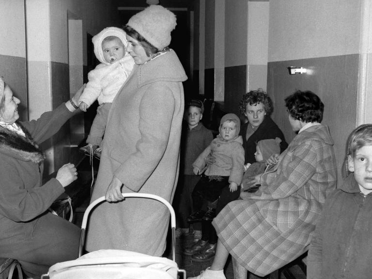 Einige aus der DDR geflüchtete Frauen und Kinder auf einem Flur.