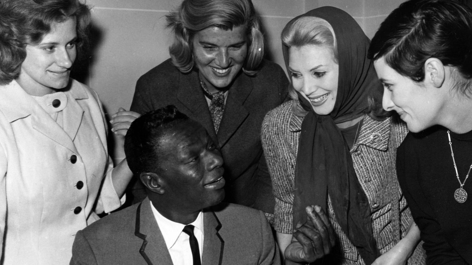 Der amerikanische Sänger Nat "King" Cole umrandet von Frauen Der amerikanische Sänger Nat "King" Cole umrandet von Frauen