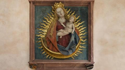 Ein Relief zeigt Maria und das Jesuskind von goldenen Strahlflammen umgeben.