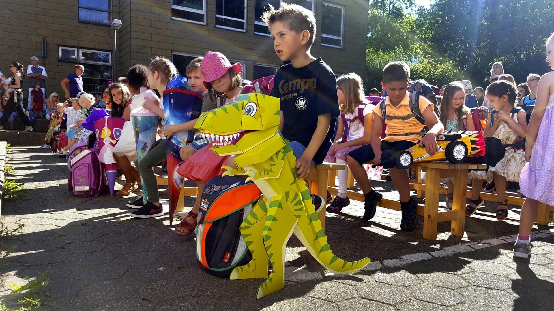 I-Maennchen bei der Einschulung mit Ihren Schultueten auf dem Schulhof, im Vordergrund ein Kind mit Dinosaurier-Schultuete, Deutschland.