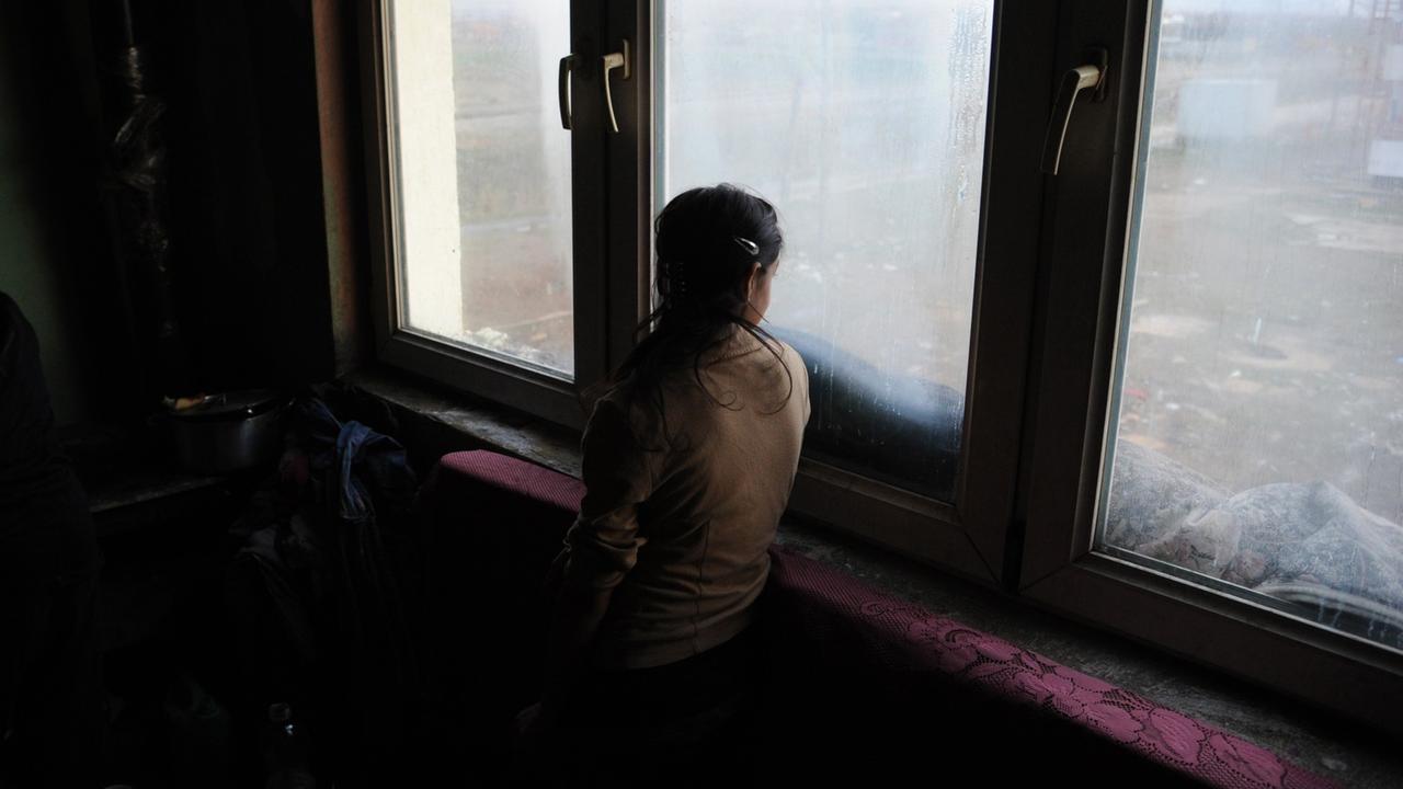 Eine Mädchen schaut Plementina bei Pristina im Kosovo aus dem Fenster einer Wohnung  fotografiert am 