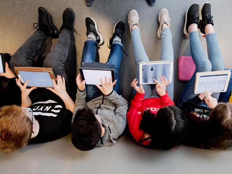Schüler sitzen in einer Reihe und lernen mit Laptops.