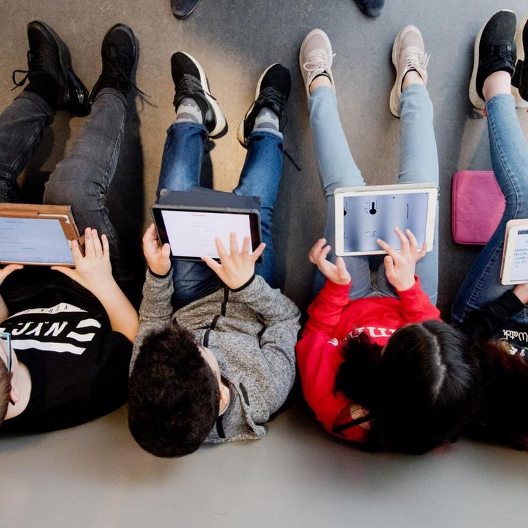 Schüler sitzen in einer Reihe und lernen mit Laptops.