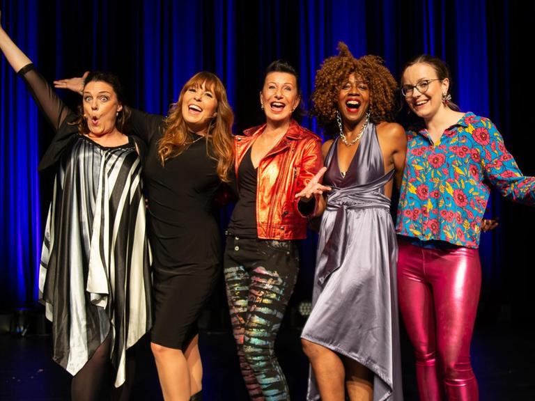 Fünf Kabarettistinnen stehen auf einer Bühne nebeneinander: Rebecca Carrington, Katie Freundenschuss, Patrizia Moresco, Tamika Campbell, Helene Bockhorst