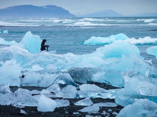 Ein Mann sitzt im schmelzenden Eis am Meeresstrand.
