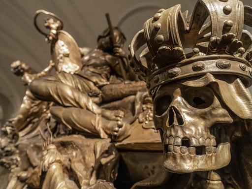 Ein metallener Totenkopf mit Krone und fehlenden Zähnen.