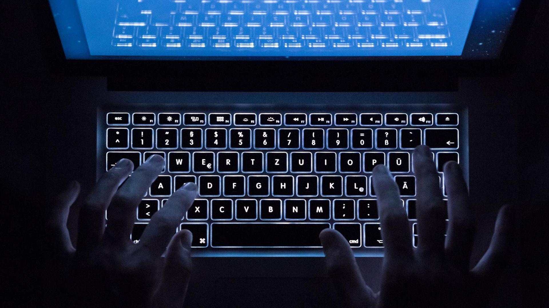 Hande über einer beleuchteten Computertastatur Hande über einer beleuchteten Computertastatur
