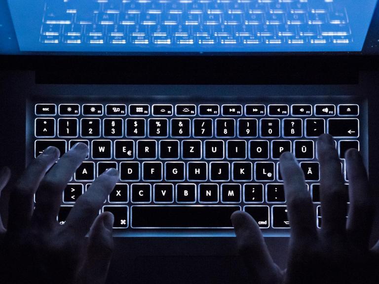 Hande über einer beleuchteten Computertastatur